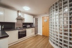 Modern kitchen with a curved glass block wall and white cabinetry.