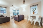 Bright living room with grey sofas, TV, and dining area near windows chancellors