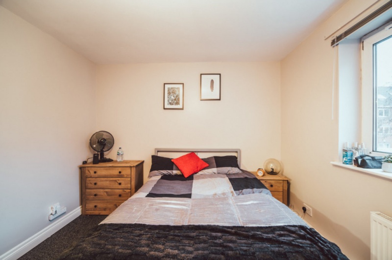 Cozy bedroom with a large bed, wooden nightstands, and framed wall art.