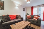 Living room with grey and red decor, including two sofas and a wooden coffee table.