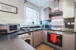 Compact kitchen with modern appliances, a window, and grey cabinetry at Mayfair Court