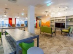 Modern dining area at Plymouth Cross House with white tables and green chairs.