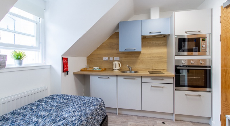 Well-organized student room at Goods Corner with a single bed, desk, kitchenette