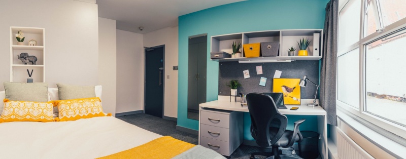 The Interior of a student bedroom at at Pennine House in Leicester features a bed, desk, and storage