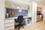 A tidy workspace in a premium townhouse studio featuring a desk, chair, and shelves for storage