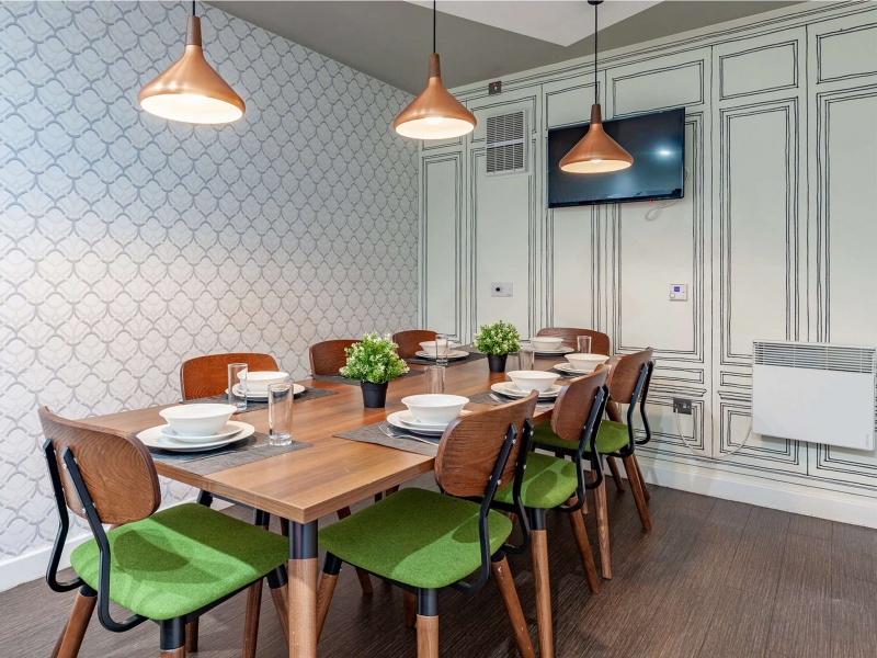 A modern shared kitchen space with a dining table, appliances, and contemporary design.