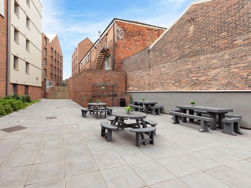  spacious outdoor courtyard with seating areas, tables, and a staircase leading up to the accommodat