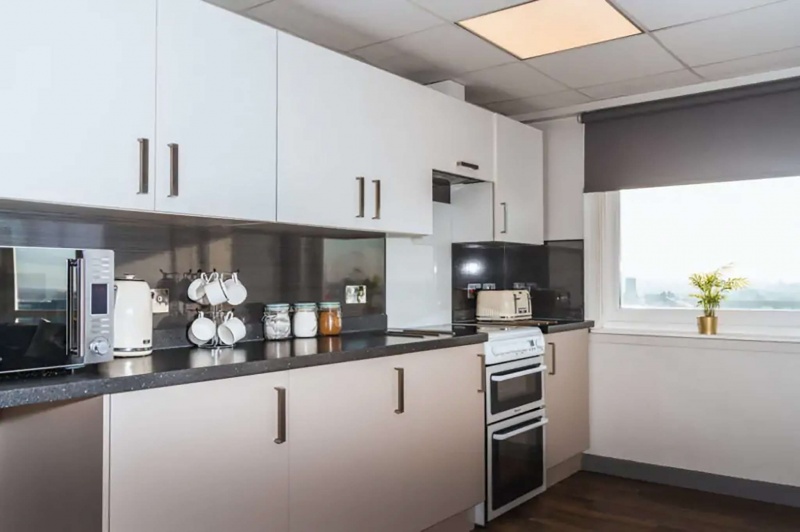  Modern kitchen at The Junxion with white cabinets, appliances, and a window view