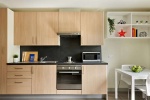 A well-equipped kitchen area in a studio, featuring wooden cabinets, a microwave, and a dining table