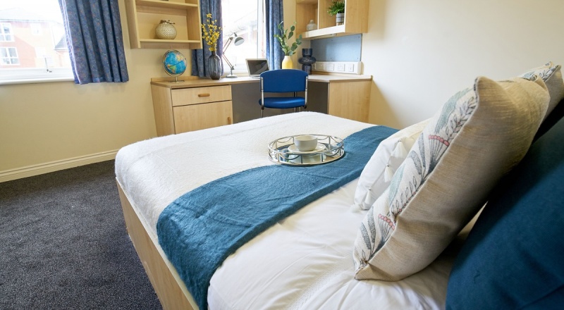 View of student room, bed, study table, window in Trinity Student Village